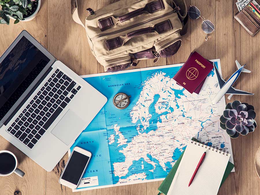 Laptop and travel items scattered on table top