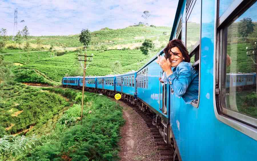 smiling woman looks out from a train window in Sri Lanka