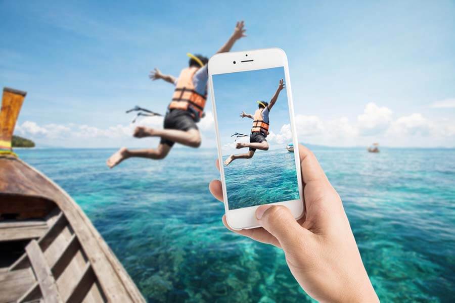 Someone taking a photo of a boy jumping off a boat 