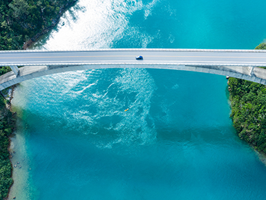 Car driving over bridge with a river underneath 