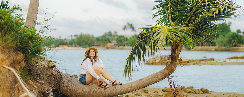 Woman sitting on palm tree in tropical location