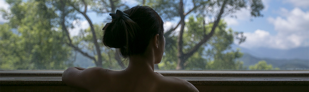 Woman in onsen looking out at scenery